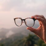 Osoba trzymająca okulary i patrząca przez nie na krajobraz, sennik okulary